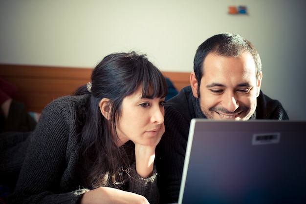 couple in love on the bed using notebook