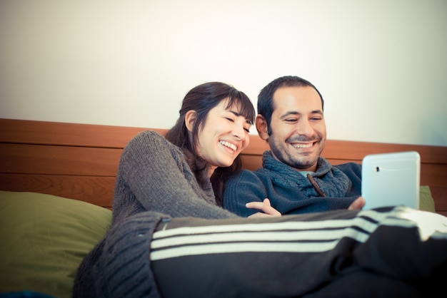 couple in love on the bed using tablet 