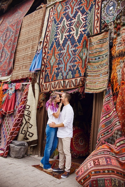 Couple in love buys a carpet and handmade textiles at an oriental market in Turkey. Hugs and cheerful happy faces of men and women