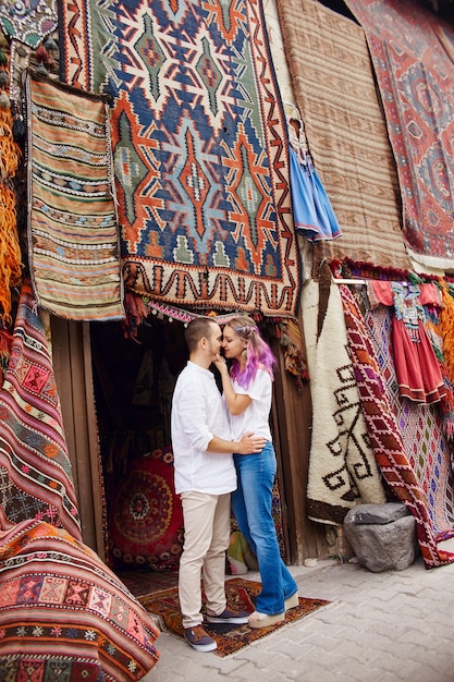 Couple in love buys a carpet and handmade textiles at an oriental market in turkey. hugs and cheerful happy faces of men and women