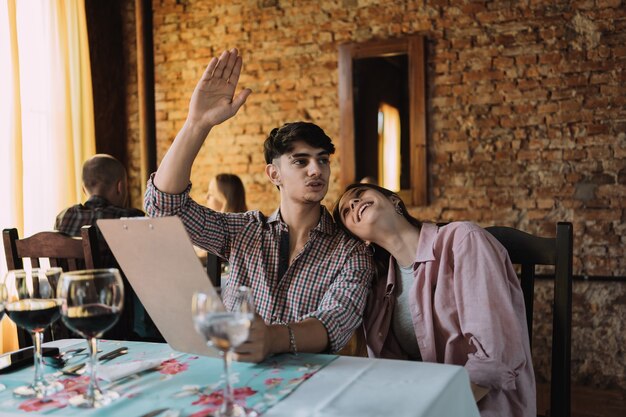 Couple in love call the waiter at the restaurant