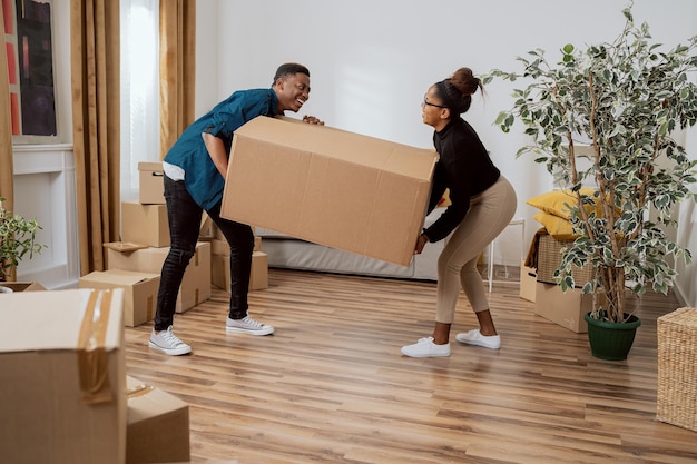 A couple in love carry heavy boxes of packed belongings out of home while moving to new apartment