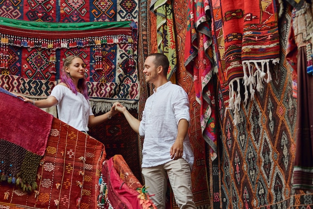 Una coppia innamorata sceglie un tappeto turco al mercato. allegre emozioni gioiose sul volto di un uomo e di una donna
