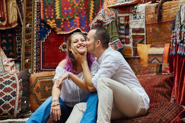 Couple in love chooses a Turkish carpet at the market. Cheerful joyful emotions on the face of a man and a woman