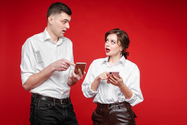 Couple in love communicates with each other, picture isolated on red wall