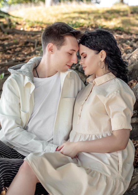 A couple in love, a couple and a girl sit under a beautiful tree and caress each other, kiss