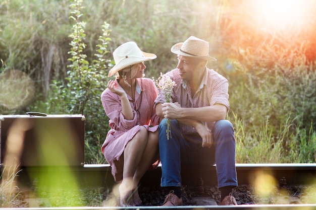 Couple in love cowboys with suitcase near railway