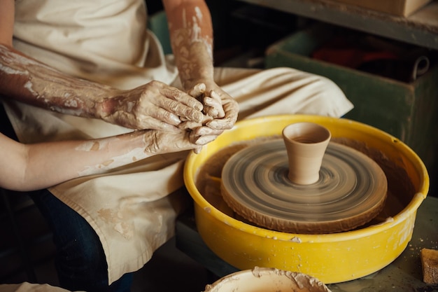 A couple in love creates a joint cup in a pottery workshop potter making ceramic pot on the pottery ...