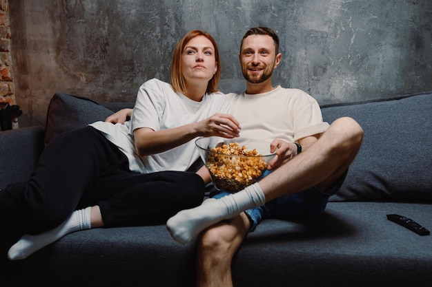 A couple in love eating popcorn are sitting at home Evening movie viewing on TV