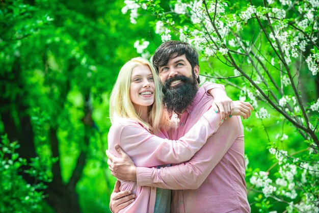 Couple in love embrace and blow dandelion Lovely couple embrace in spring garden Lovely spring day