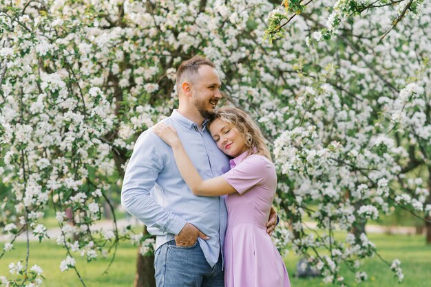 Couple in love embraces in blooming gardens in spring