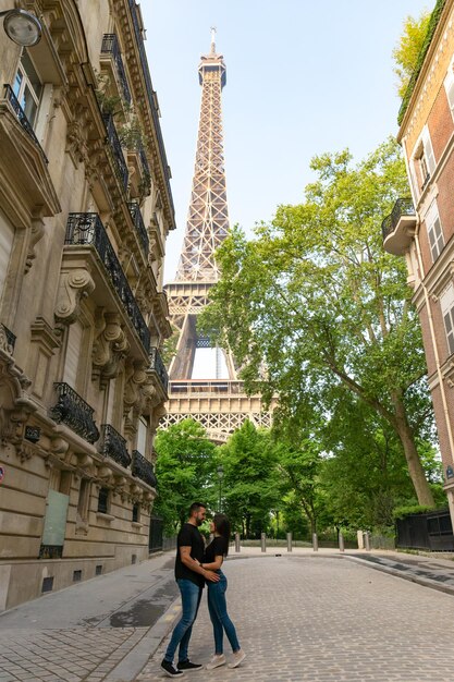 Couple in love embracing and gazing at each other with the eiffel tower in Paris