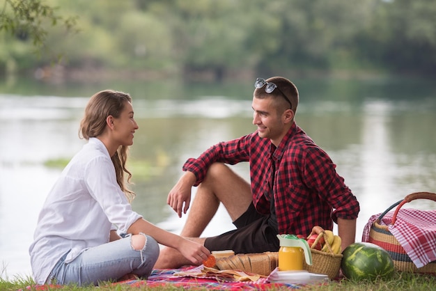 Couple in love enjoying picnic time drink and food in beautiful nature on the river bank