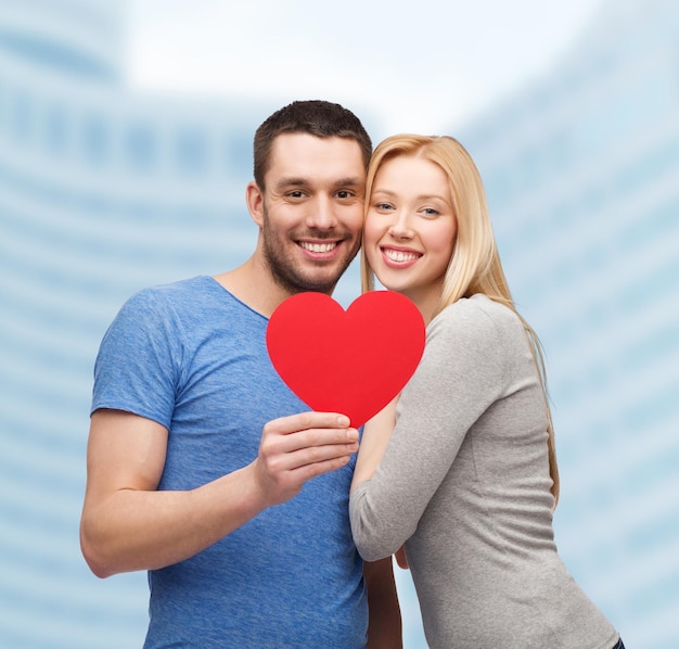 couple, love and family concept - smiling couple holding big red heart