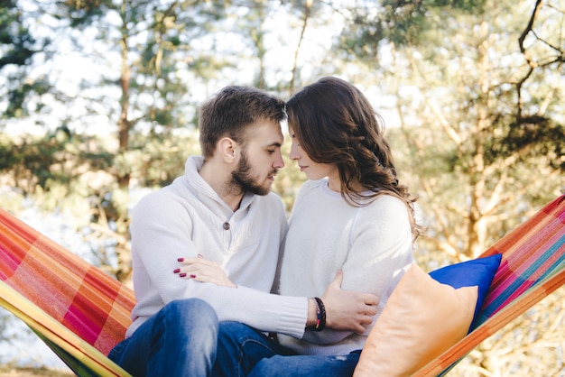 Couple in love, girl and guy in hammock enjoys in the woods, travel love story concept