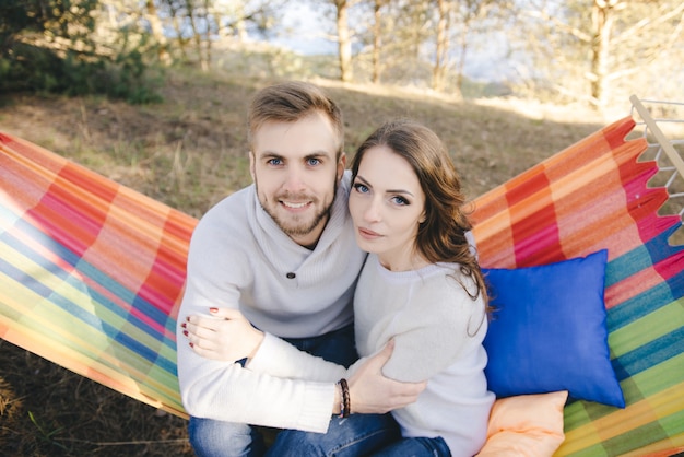 Foto coppia in amore, ragazza e ragazzo in amaca gode nel bosco, concetto di storia d'amore di viaggio