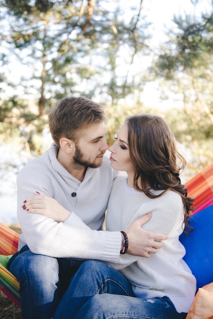 Couple in love girl and guy in hammock enjoys in the woods travel love story concept