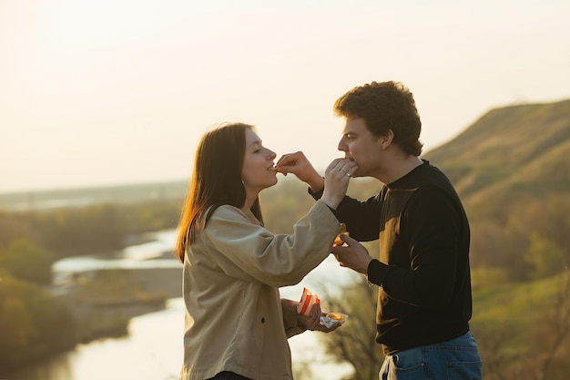 couple in love guy and girl feed each other french fries in nature