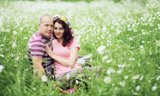 Couple in love guy and girl in a field of white daisies and green grass.