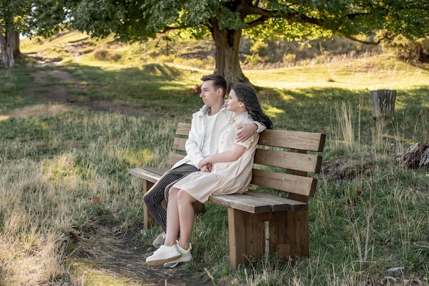 A couple in love, a guy and a girl sit on a bench and caress each other, kiss