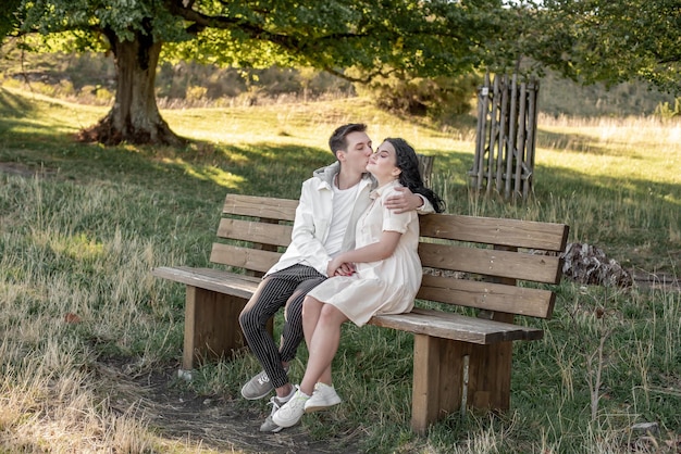 A couple in love, a guy and a girl sit on a bench and caress each other, kiss