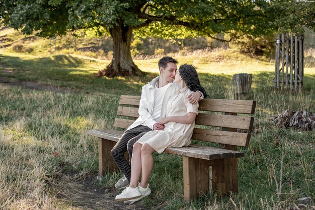 A couple in love, a guy and a girl sit on a bench and caress each other, kiss