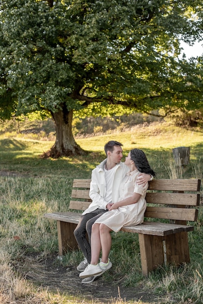 A couple in love, a guy and a girl sit on a bench and caress each other, kiss