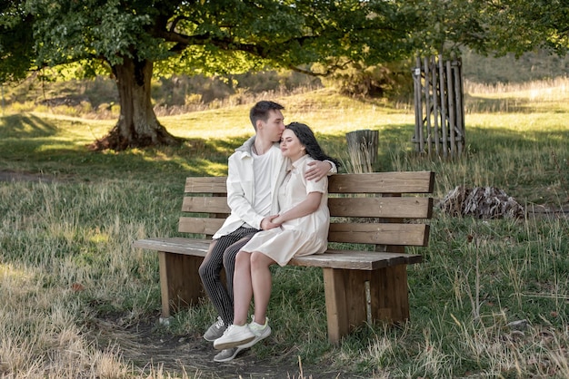 Photo a couple in love, a guy and a girl sit on a bench and caress each other, kiss