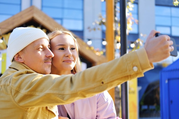 A couple in love a guy and a girl take a selfie together in sunny weather couple looking at camera and smiling