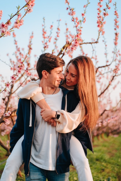 Couple in love happy as they look at each other and love each other together in fields full of pink and white flowers