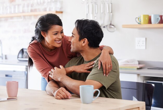 夫婦は幸せを愛し、サポートやケアの会話の抱擁を愛し、台所のテーブルで一緒に話し、結婚したアジア人男性と女性の愛情、または家族の家で健康的な絆とロマンチックな笑顔を愛する