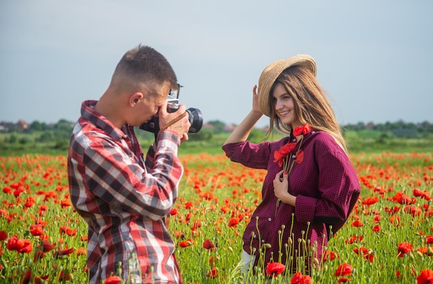 Photo couple in love having romantic date in poppy flower field with photo camera photographing