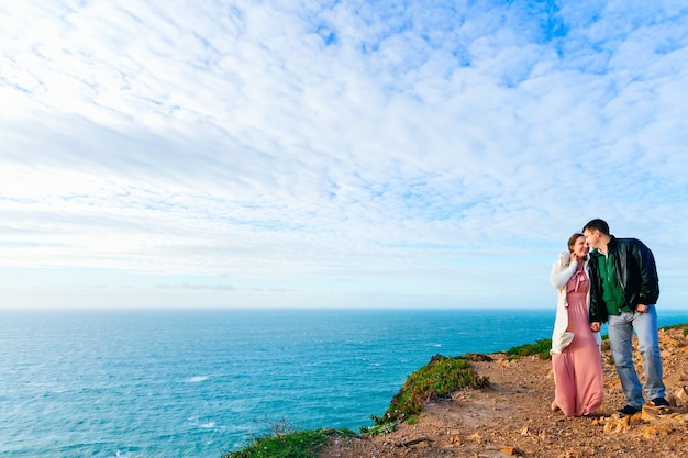 A couple in love hold hands on the high ocean shore.