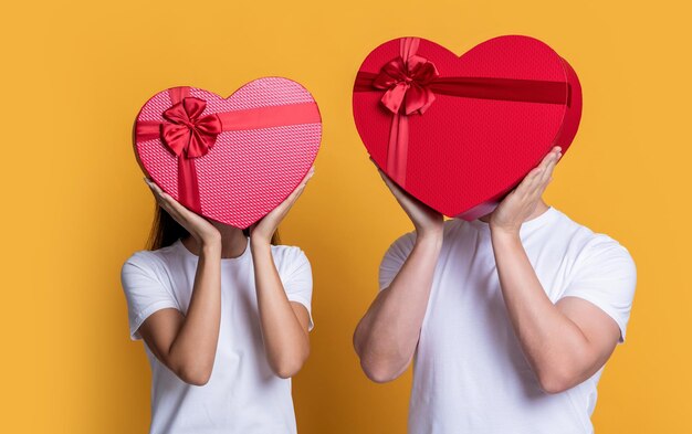 Couple in love hold valentine present isolated on yellow couple with valentine love present