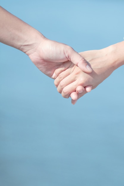 Couple love holding hands on blue sky and sea background. 