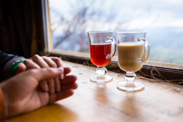 뜨거운 커피나 차를 마시는 손을 잡고 사랑에 빠진 커플과 산 Carpathians에서 휴식
