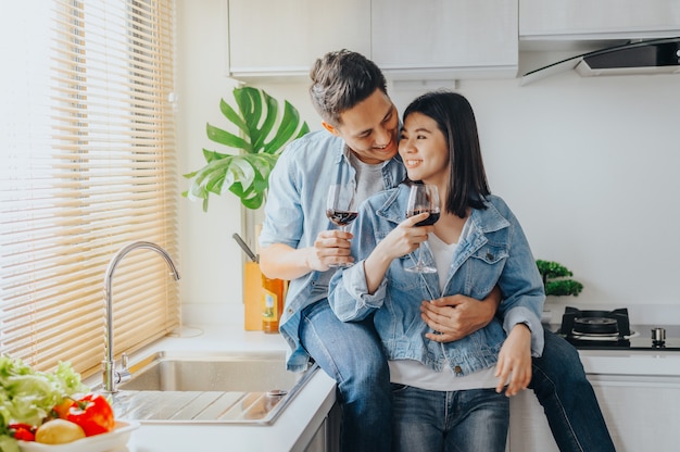 Couple in love hugging and drinking red wine in the kitchen