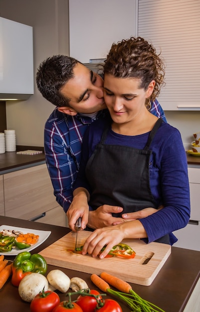 Couple in love hugging and preparing healthy vegetables in the kitchen. Modern family lifestyle concept.