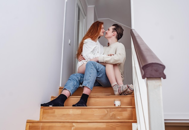 Couple in love hugging on wooden stairs Redhaired young woman with bare legs in the arms