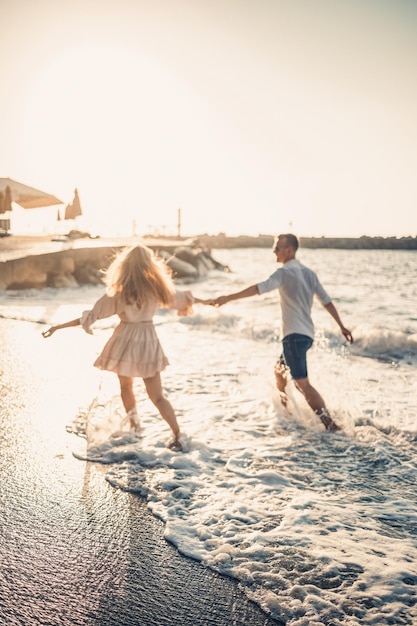 A couple in love is walking on the beach near the sea Young family at sunset by the mediterranean sea Summer vacation concept