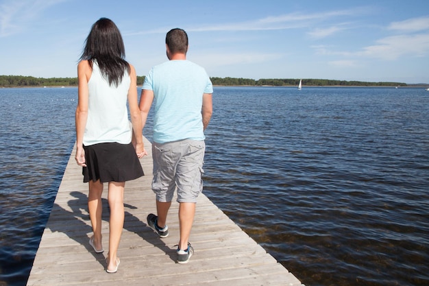 Couple in love is walking on pontoon wood at lake side