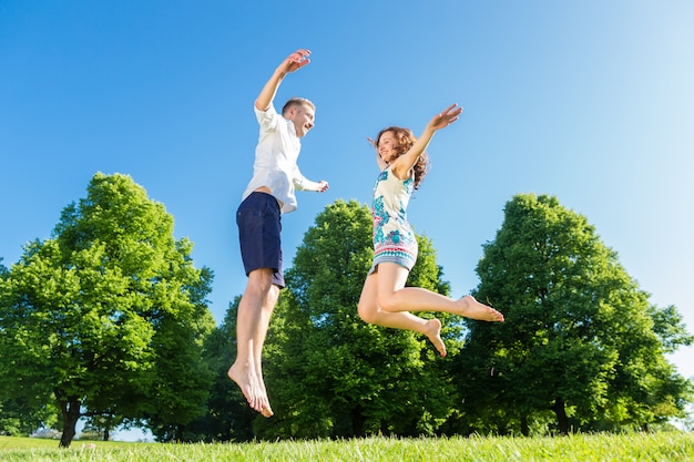 Photo couple in love jumping on park lawn