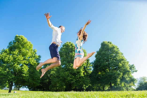 Couple in love jumping on park lawn