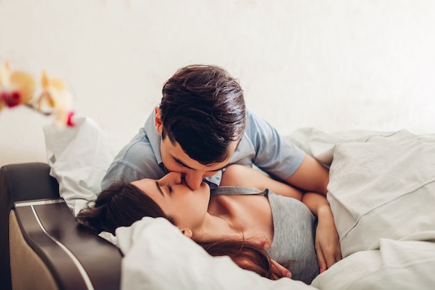 朝ベッドで横になっているキスの愛のカップル。