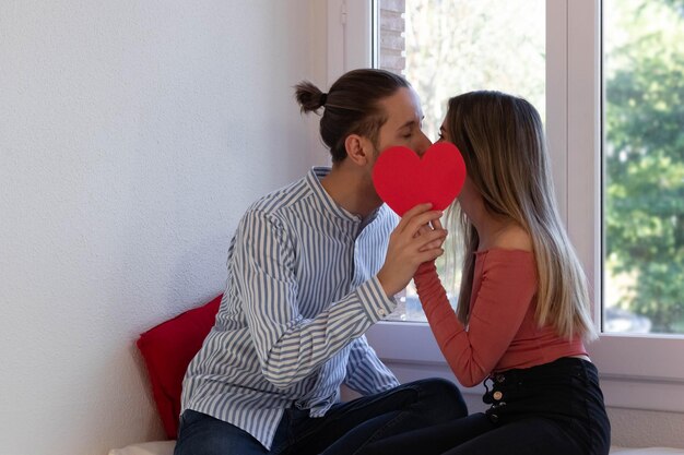 Couple in love kissing behind a red heart