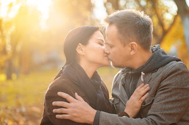 太陽に輝く夫と彼の妻が秋の日当たりの良い牧草地でキスするのが大好きなカップル...