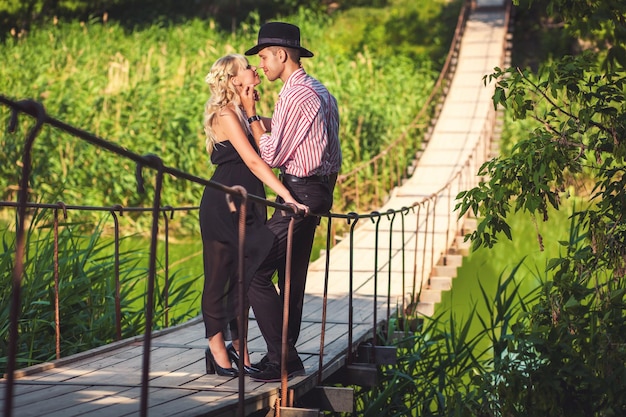 Couple in love looking at each other on wooden long bridge