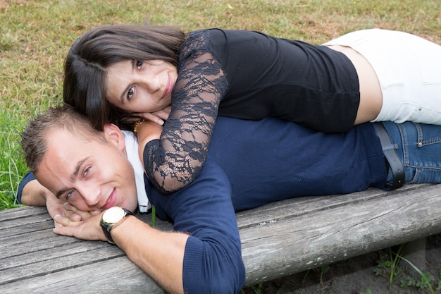 Couple in love lying on bench in park