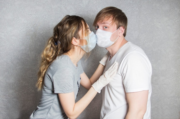 A couple in love a man and a woman kiss each other in a protective medical mask on their face