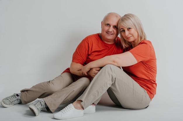 влюбленная пара в оранжевых футболках смеется и обнимается на белом фоне